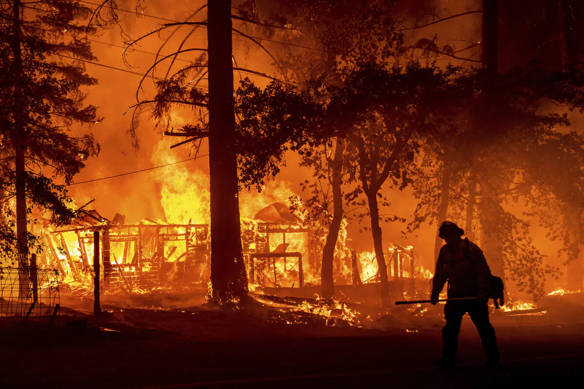 A firefighter passes a burning home as the Dixie Fire flares in Plumas County, Calif., on July 24, 2021. (Noah Berger/AP)