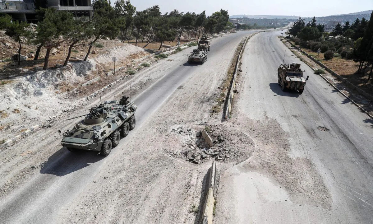 Russian and Turkish military armoured vehicles and armoured personnel carriers drive together in a joint patrol along the M4 highway, which links the northern Syrian provinces of Aleppo and Latakia, near Ariha in Syria's rebel-held northwestern Idlib province, on July 7, 2020. (Omar Haj Kadour/AFP via Getty Images)