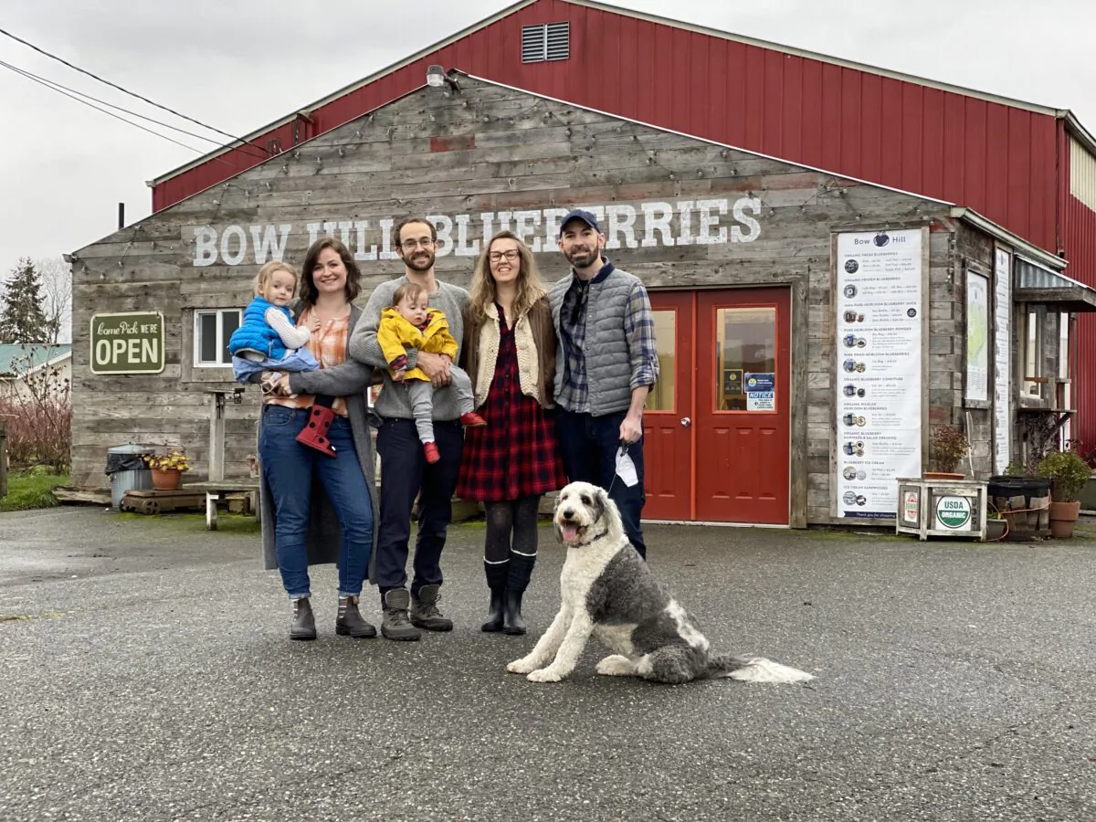 (L–R) Vera, Emma, Ezra, and Soren Ranz; Audrey and Andrew Matheson; and Saoirse the sheepadoodle in front of the Bow Hill farm store in Bow, Wash. (Courtesy of Bow Hill Blueberries)