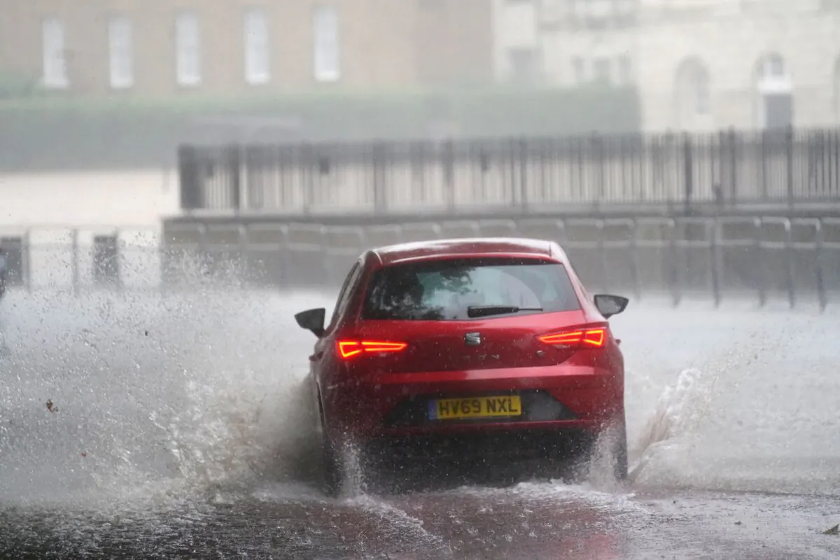 A car drives through flood water in Horse Guards Road in central London on July 25, 2021. (Victoria Jones/PA)