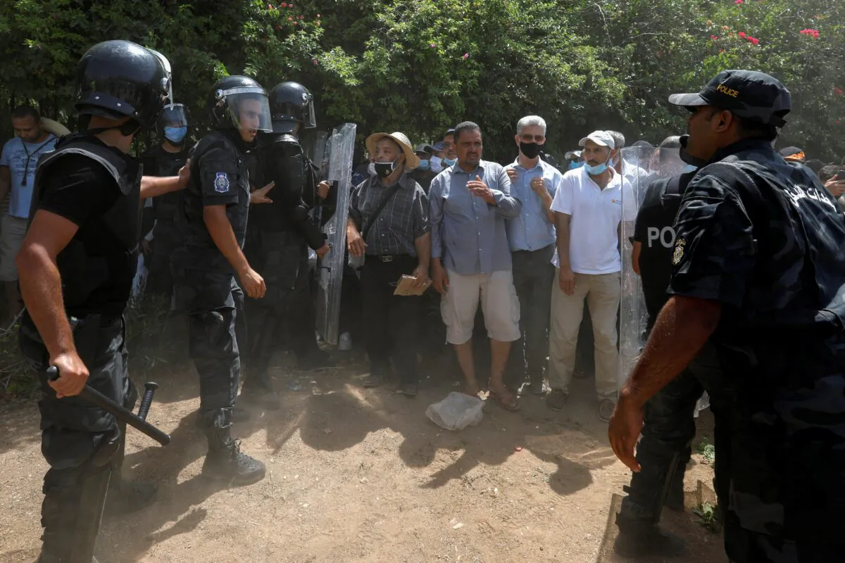 Police officers hold back supporters of Tunisia's biggest political party, the moderate Islamist Ennahda, as they attempt to reach the Parliament building in Tunis, Tunisia, on July 26, 2021. (Zoubeir Souissi/Reuters)