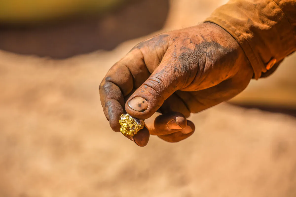 A hand holding a gold nugget. (Emmerson Resources)