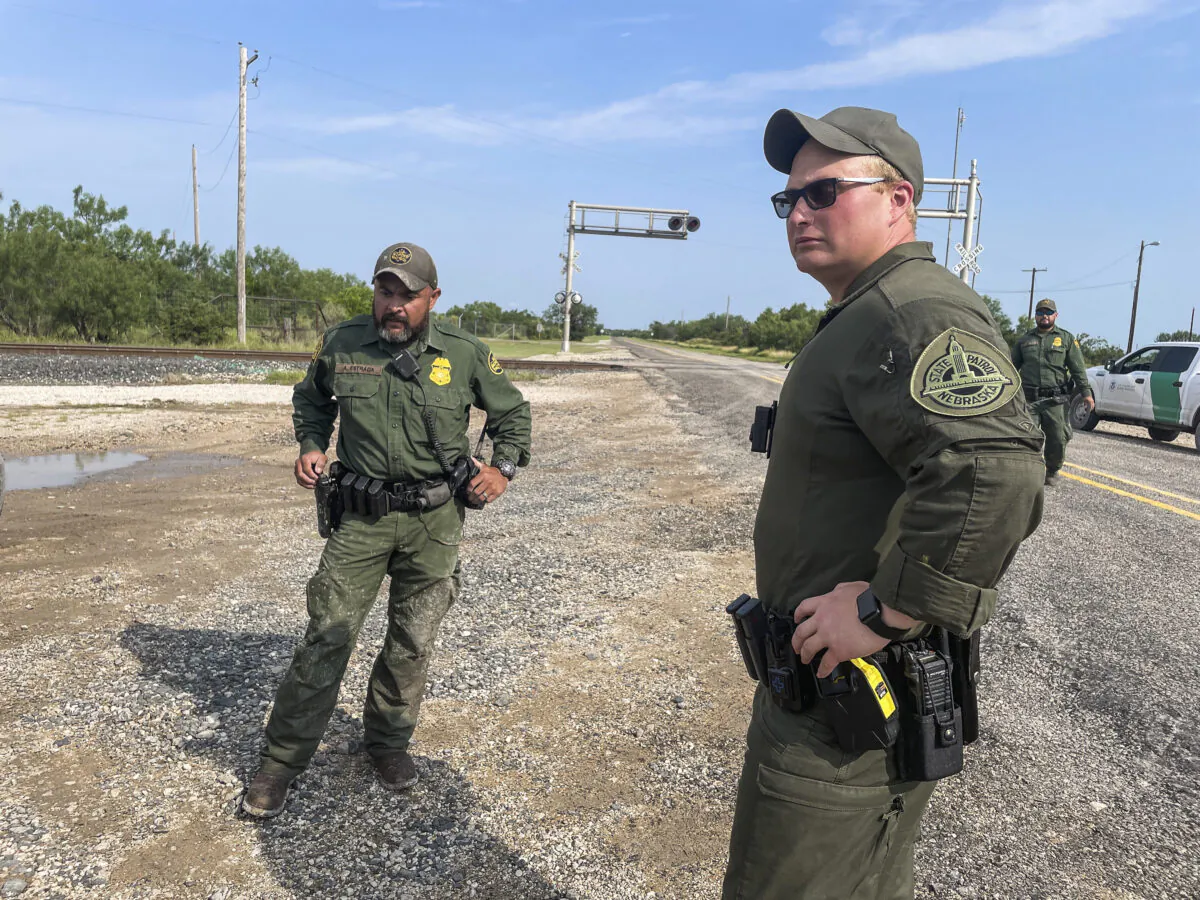 A Nebraska State Trooper (C) assists Border Patrol in detaining illegal immigrants while deployed to Texas, in Kinney County, Texas, on July 21, 2021. (Charlotte Cuthbertson/The Epoch Times)