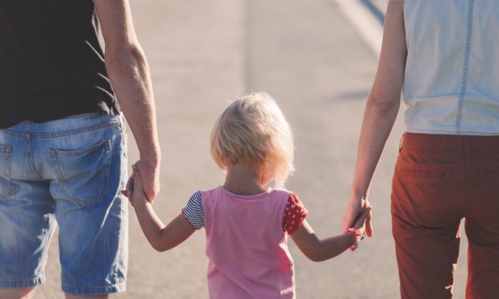 A photo of a child holding hands with two adults. (Pexels from Pixabay)