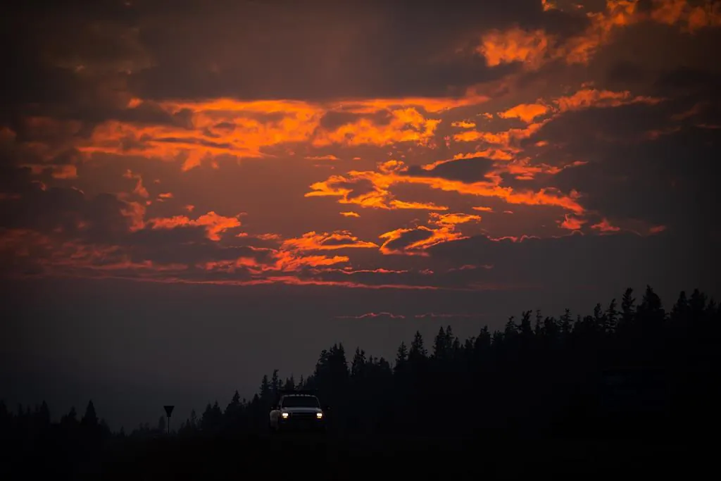 Smoke particles from wildfires enhance the colour of a sunset as a motorist travels on Highway 97C near Logan Lake, B.C., on July 15, 2021. Above average temperatures for many parts of B.C. aren't expected to ease soon and Environment Canada says there is no hint of showers until at least the weekend for some regions of southern B.C. hit hard by wildfires. (The Canadian Press/Darryl Dyck)