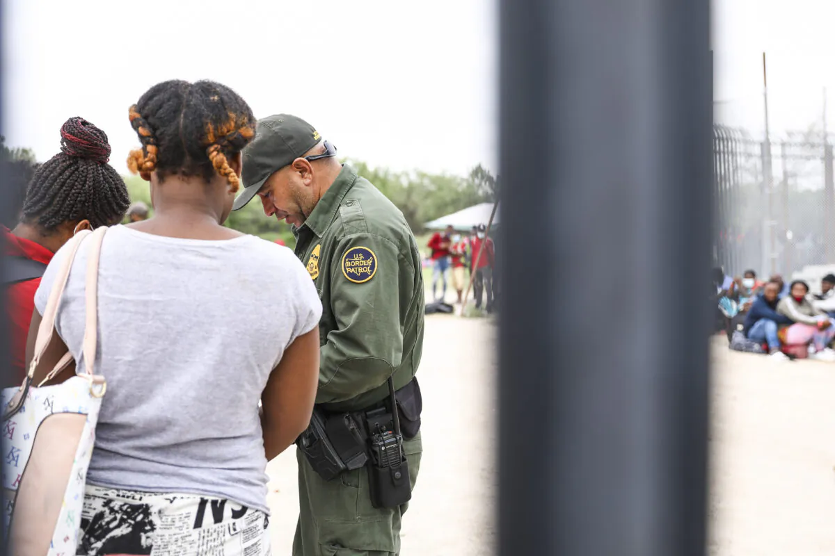 A Border Patrol agent starts organizing a group of more than 350 illegal immigrants after they crossed the Rio Grande from Mexico into Del Rio, Texas, on July 25, 2021. (Charlotte Cuthbertson/The Epoch Times)