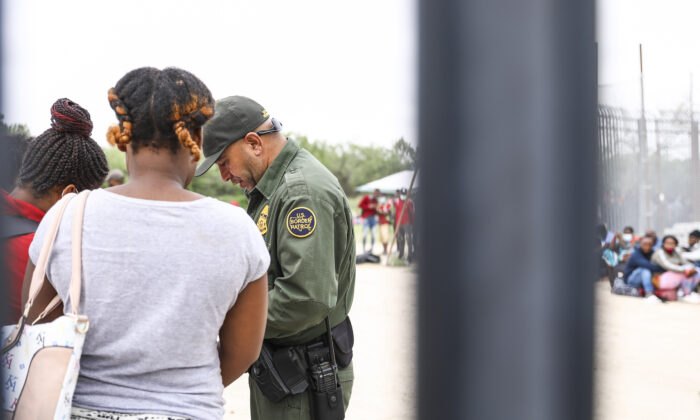 A Border Patrol agent starts organizing a group of more than 350 illegal immigrants after they crossed the Rio Grande from Mexico into Del Rio, Texas, on July 25, 2021. (Charlotte Cuthbertson/The Epoch Times)