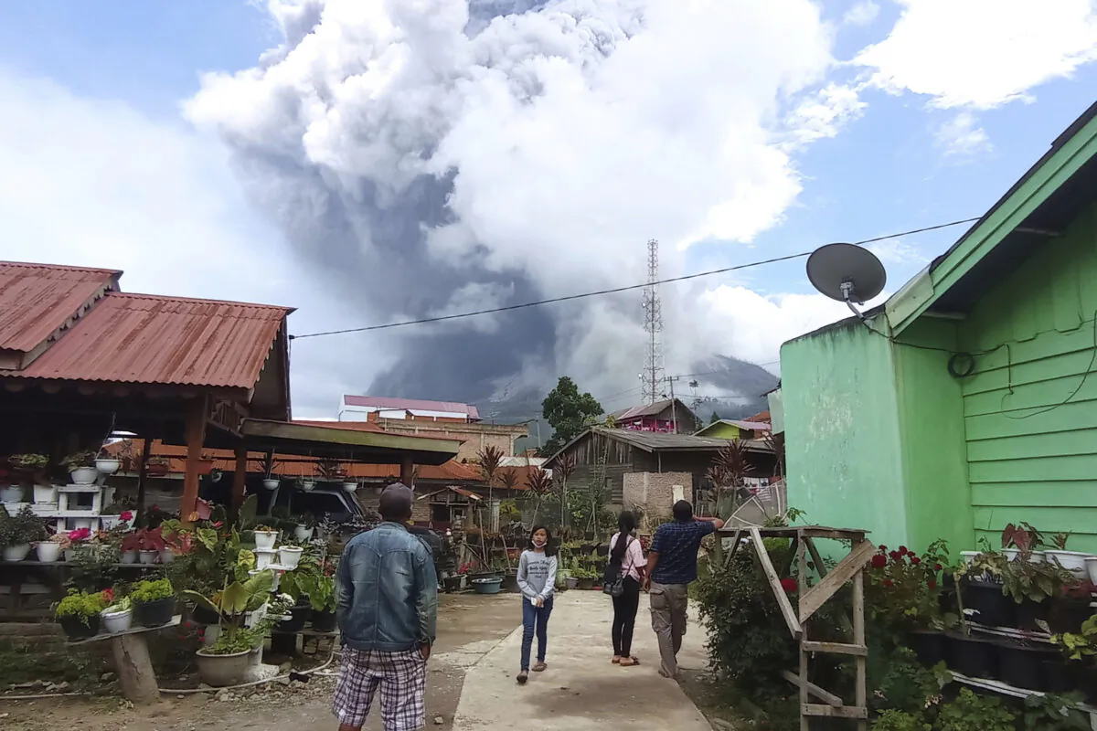 People watch as Mount Sinabung spews volcanic materials during an eruption in Karo, North Sumatra, Indonesia on Wednesday, July 28, 2021. (Sastrawan Ginting/AP Photo)