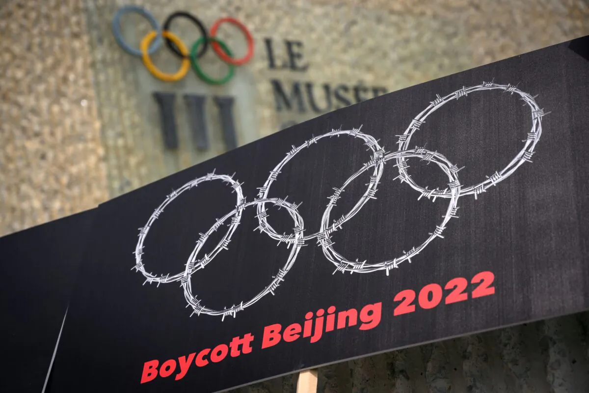 A placard with barbed wire in the shape of the Olympics Rings is seen next to a sign of the Olympics Museum during a protest organised by Tibetan and Uyghur activists against Beijing 2022 Winter Olympics, in Lausanne, Switzerland, on June 23, 2021. (Fabrice Coffrini/AFP via Getty Images)