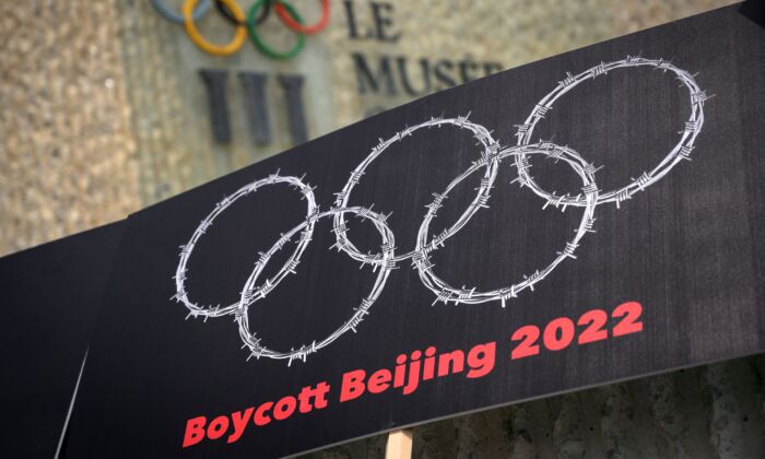 A placard with barbed wire in the shape of the Olympics Rings is seen next to a sign of the Olympics Museum during a protest organised by Tibetan and Uyghur activists against Beijing 2022 Winter Olympics, in Lausanne, Switzerland, on June 23, 2021. (Fabrice Coffrini/AFP via Getty Images)