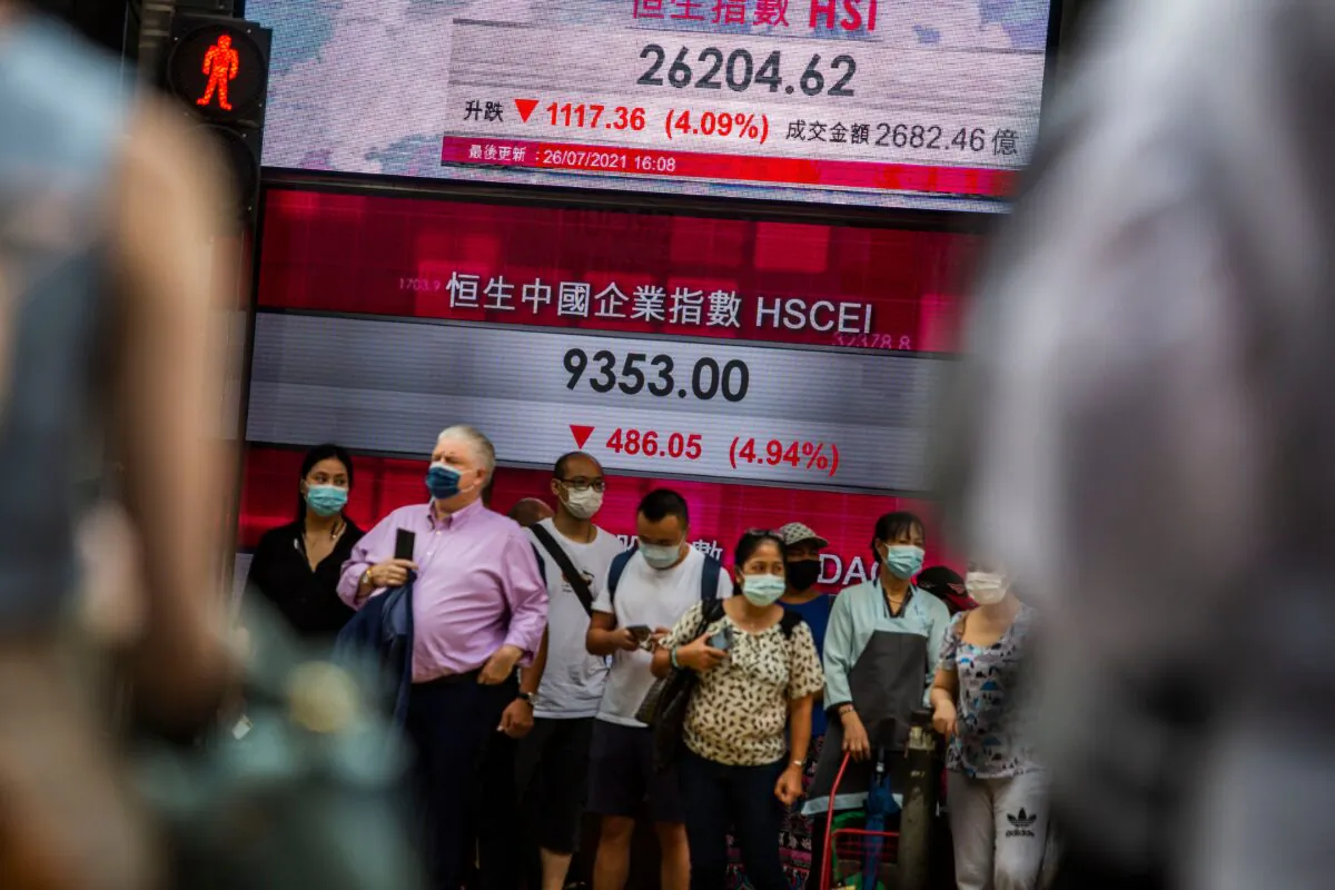 People stand in front of an electronic display showing the Hang Seng Index in the Central district of Hong Kong on July 26, 2021. (Isaac Lawrence/AFP via Getty Images)