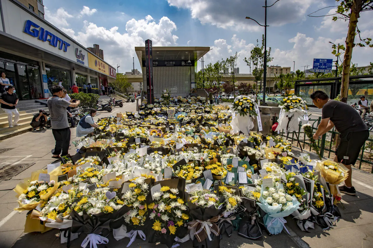 A man places flowers with other bouquets in front of a subway station in memory of flood victims in Zhengzhou, central China's Henan Province, on July 27, 2021. (STR/AFP via Getty Images)