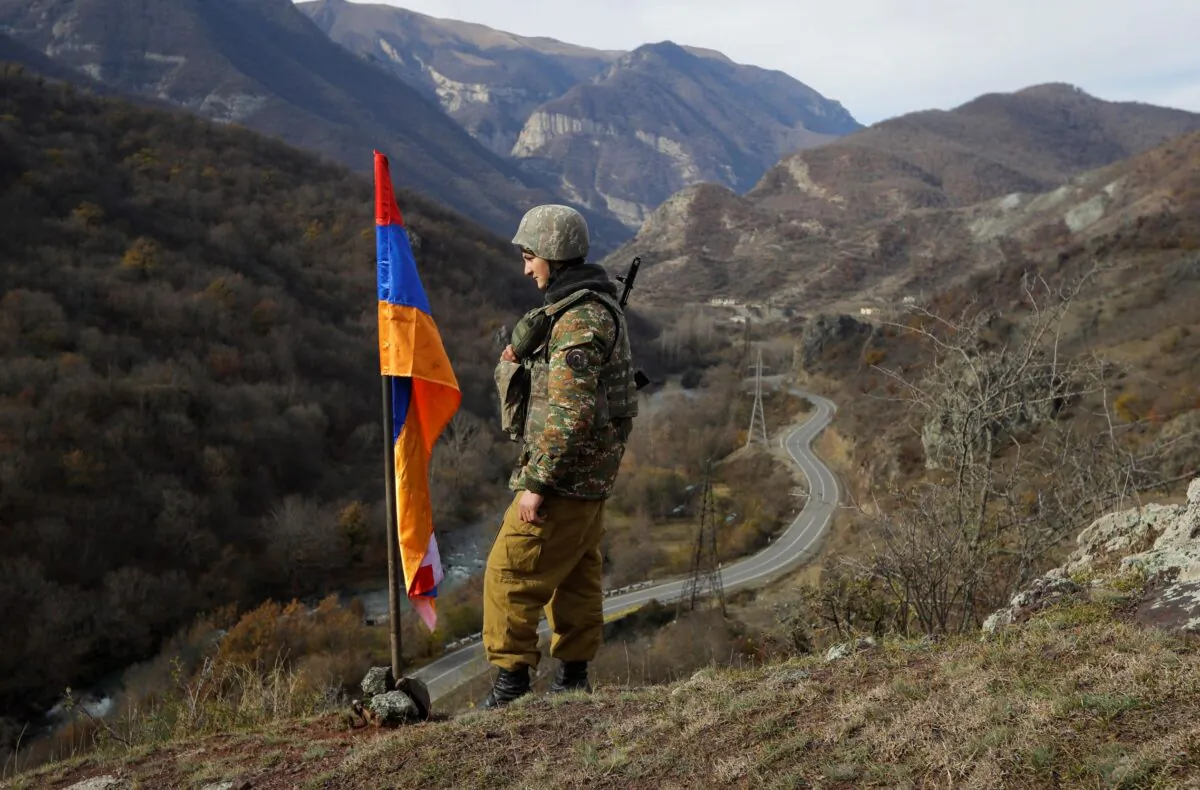 An ethnic Armenian soldier stands guard next to Nagorno-Karabakh's flag atop the hill near Charektar in the separatist region of Nagorno-Karabakh at a new border with Kalbajar district turned over to Azerbaijan, on Nov. 25, 2020. (Sergei Grits/AP Photo)