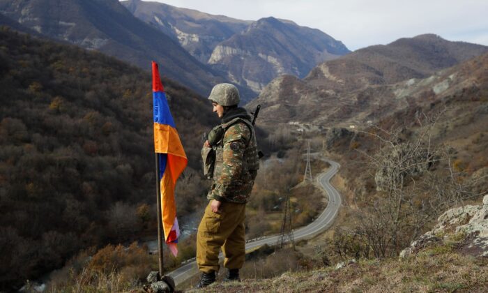 An ethnic Armenian soldier stands guard next to Nagorno-Karabakh's flag atop of the hill near Charektar in the separatist region of Nagorno-Karabakh at a new border with Kalbajar district turned over to Azerbaijan, on Nov. 25, 2020. (Sergei Grits/File/AP Photo)