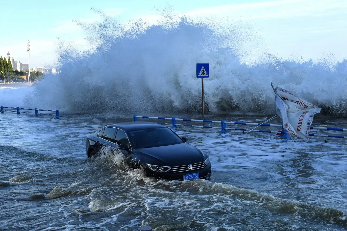A car sits in flood waters as waves, caused by Typhoon In-fa, surge over a barrier along the seacoast in China's eastern Shandong Province, on July 25, 2021. (STR / AFP)
