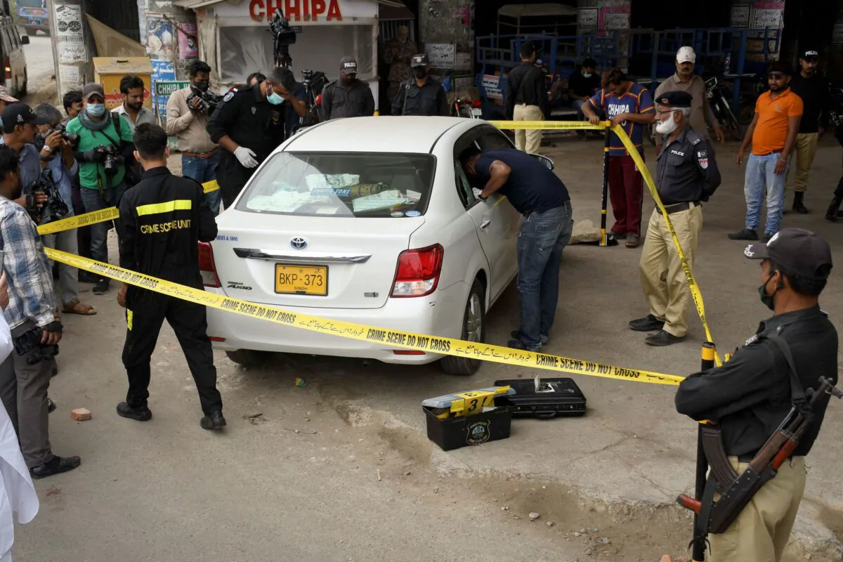 Investigators examine a damaged car at the site of a firing incident, in Karachi, Pakistan, on July 28, 2021. (Fareed Khan/AP)