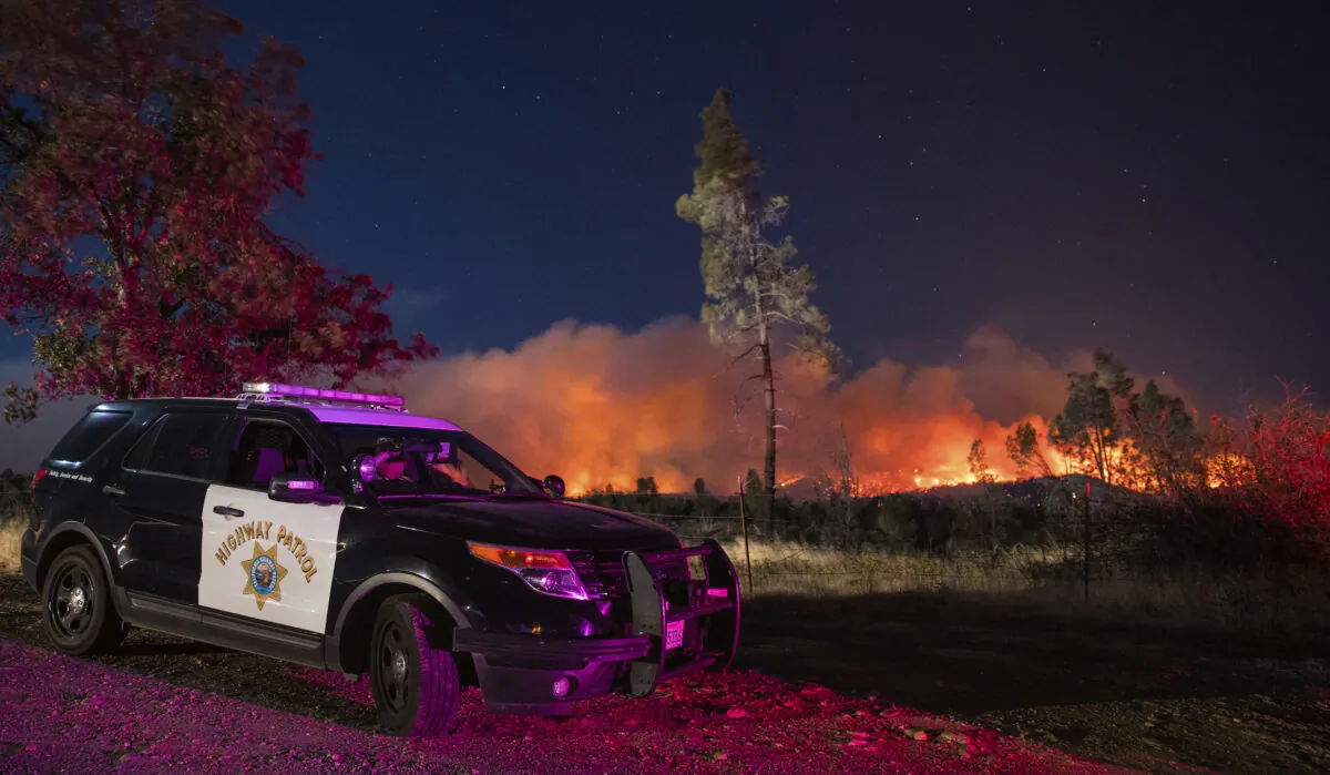 A California Highway Patrol officer watches flames that are visible from the Zogg Fire on Clear Creek Road near Igo, Calif., on Sep. 28, 2020. (Ethan Swope/AP Photo)
