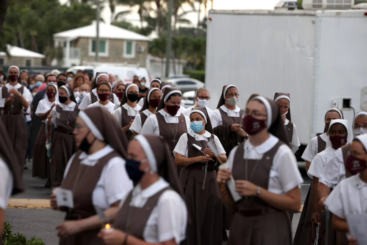 Priests and nuns carry a makeshift statue of Our Lady of Fatima past St. Joseph Church in Miami Beach before walking to a vigil to pray the rosary for victims of the collapsed 12-story Champlain Towers South condo building in Surfside, Florida, on July 7, 2021. (Anna Moneymaker/Getty Images)