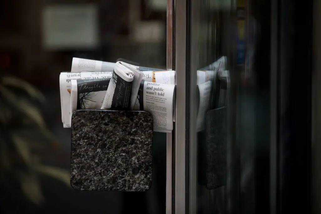 Stacks of newspapers are stuffed into a door handle of a closed building in Toronto on April 1, 2020. (Cole Burston/Getty Images)