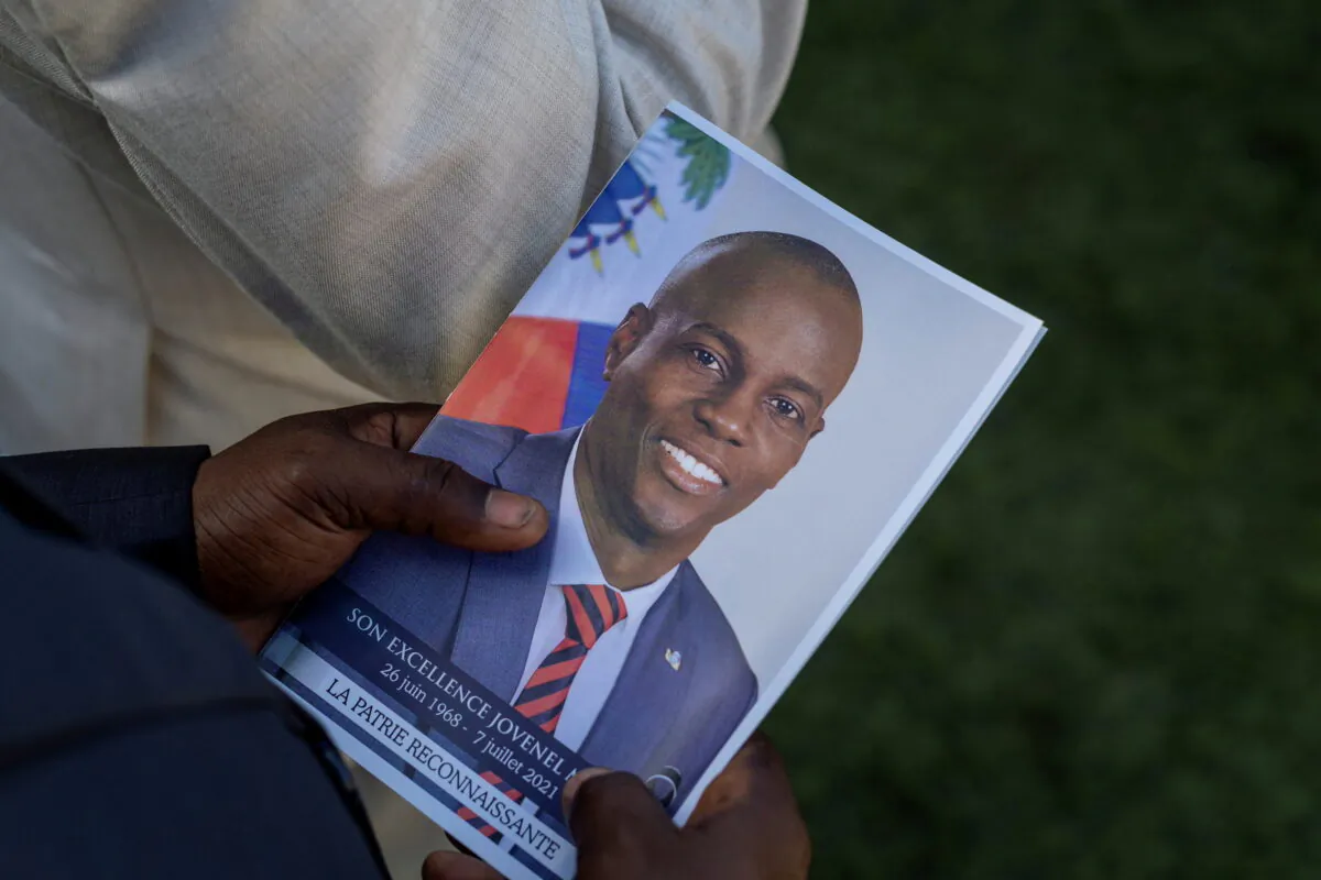 A person holds a photo of late Haitian President Jovenel Moise, who was shot dead in early July, during his funeral at his family home in Cap-Haitien, Haiti, on July 23, 2021. (Ricardo Arduengo/Reuters)
