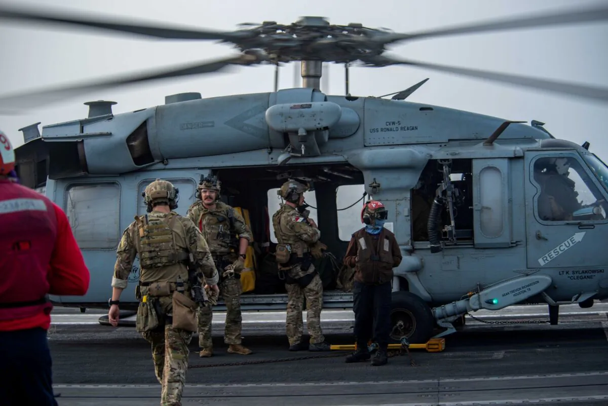 Sailors assigned to Explosive Ordnance Disposal Mobile Unit (EODMU) 5 board an MH-60S Sea Hawk helicopter, attached to the "Golden Falcons" of Helicopter Sea Combat Squadron (HSC) 12, are seen on the flight deck of aircraft carrier USS Ronald Reagan (CVN 76), in response to a call for assistance from the Mercer Street, a Japanese-owned Liberian-flagged tanker managed by Israeli-owned Zodiac Maritime, in the Arabian Sea, on July 30, 2021. (U.S. Navy/Handout via Reuters)