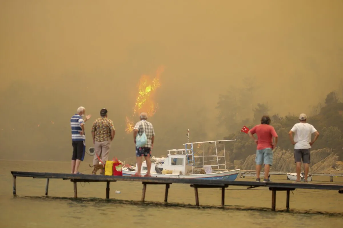 Tourists wait to be evacuated from smoke-engulfed Mazi area as wildfires rolled down the hill toward the seashore, in Bodrum, Mugla, Turkey, on Aug. 1, 2021. (Emre Tazegul/AP Photo)