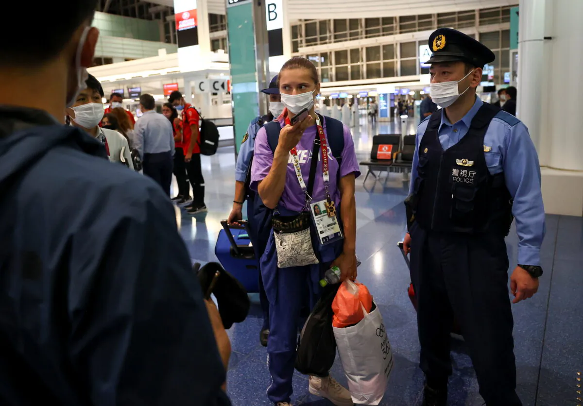 Belarusian sprinter Krystsina Tsimanouskaya is escorted by police officers at Haneda international airport in Tokyo, Japan, on Aug. 1, 2021. (Issei Kato/Reuters)