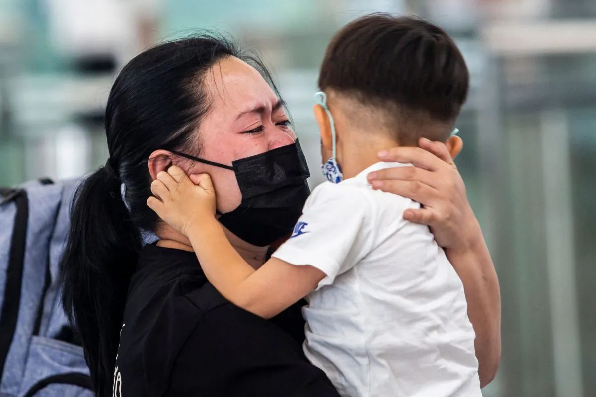 A woman is hugging a young child at the departure gates of Hong Kong's International Airport on July 19, 2021. (ISAAC LAWRENCE/AFP via Getty Images)