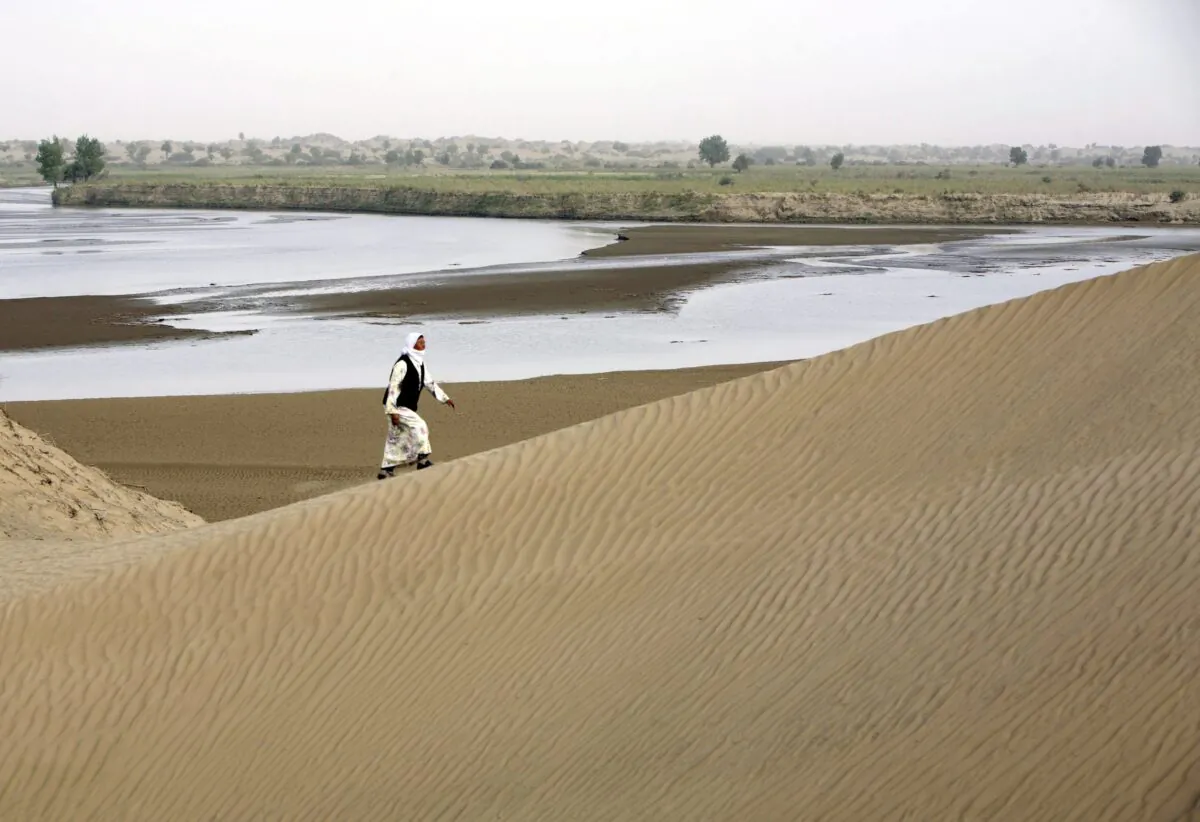 A Keriyan citizen walks on the sand dunes along the Keriyan River in Daheyan village in Yutian county of Xinjiang Region, China on Sept. 10, 2007. (China Photos/Getty Images)