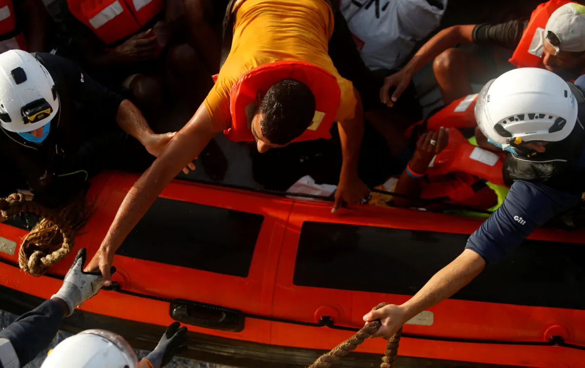 A migrant prepares to climb on board the German NGO migrant rescue ship Sea-Watch 3 from a rescue RHIB (rigid hulled inflatable boat) in international waters north of Libya, in the western Mediterranean Sea, on Aug. 2, 2021. (Darrin Zammit Lupi/Reuters)