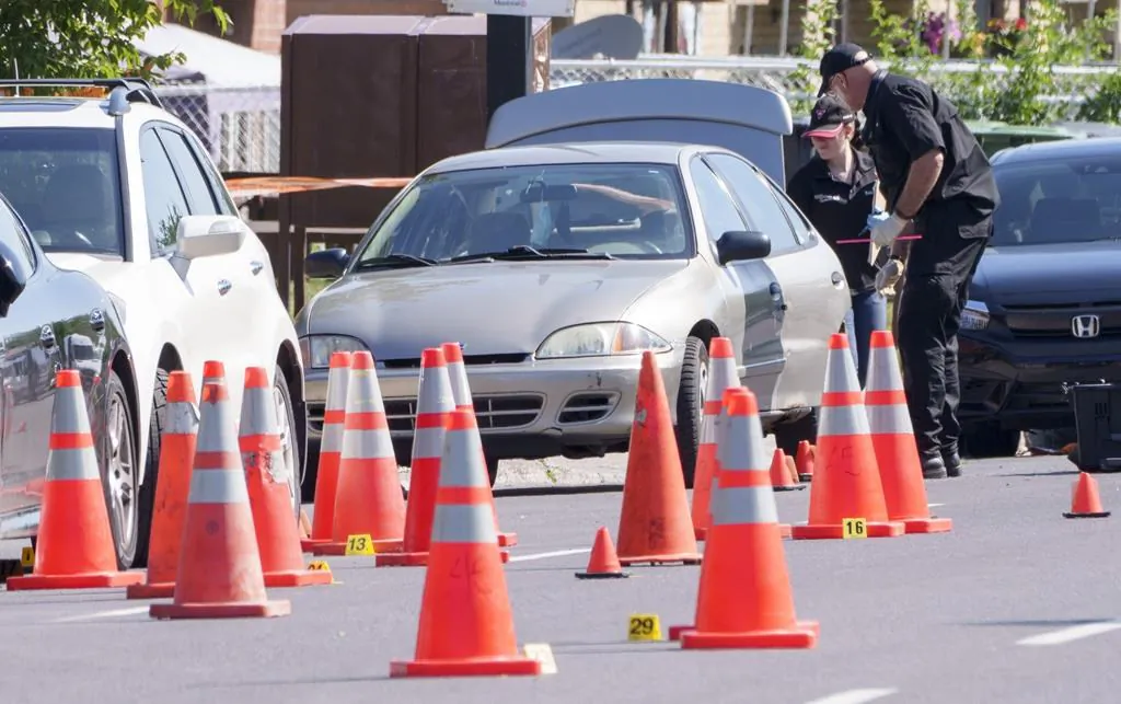 Police officers investigate a crime scene following a shooting leaving three people dead and two injured in a residential neighbourhood of Montreal on Aug. 3, 2021. (The Canadian Press/Paul Chiasson)