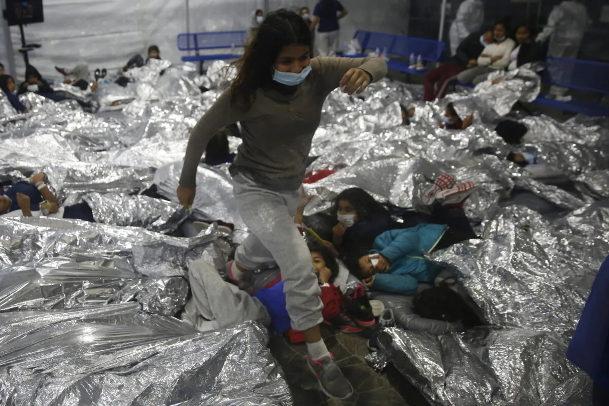 A minor walks over others inside a pod for females at the Department of Homeland Security holding facility run by the Customs and Border Patrol (CBP) in Donna, Texas, on March 30, 2021. (Dario Lopez-Mills/Pool/Getty Images)