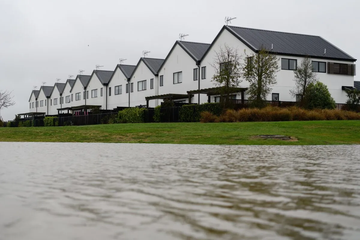 A flooded river flows next to a row of houses in Kaiapoi, New Zealand, on May 31, 2021. (Kai Schwoerer/Getty Images)