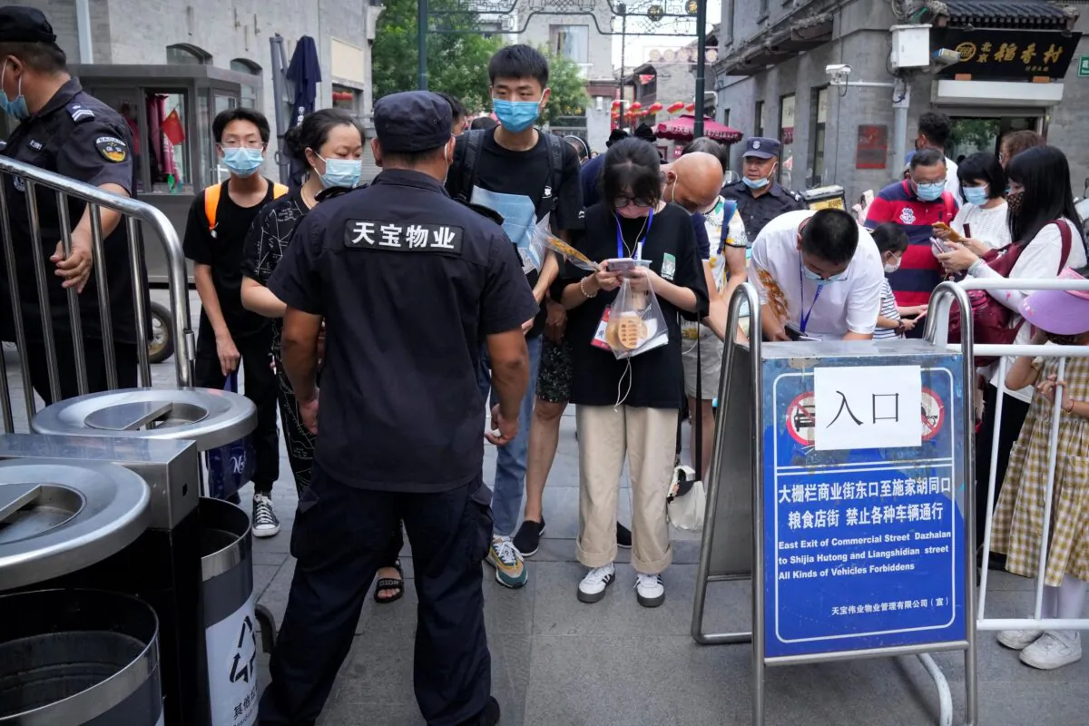 A security guard checks health codes on people’s smartphones at a tourist shopping area in Beijing, on Aug. 3, 2021. (Mark Schiefelbein/AP Photo)
