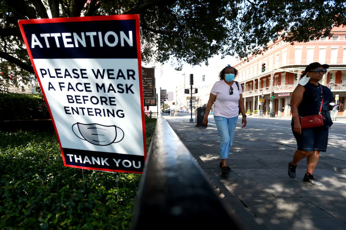 Visitors walk past mask signs along Decatur Street in the French Quarter in New Orleans, Louisiana, on July 14, 2020. (Sean Gardner/Getty Images)