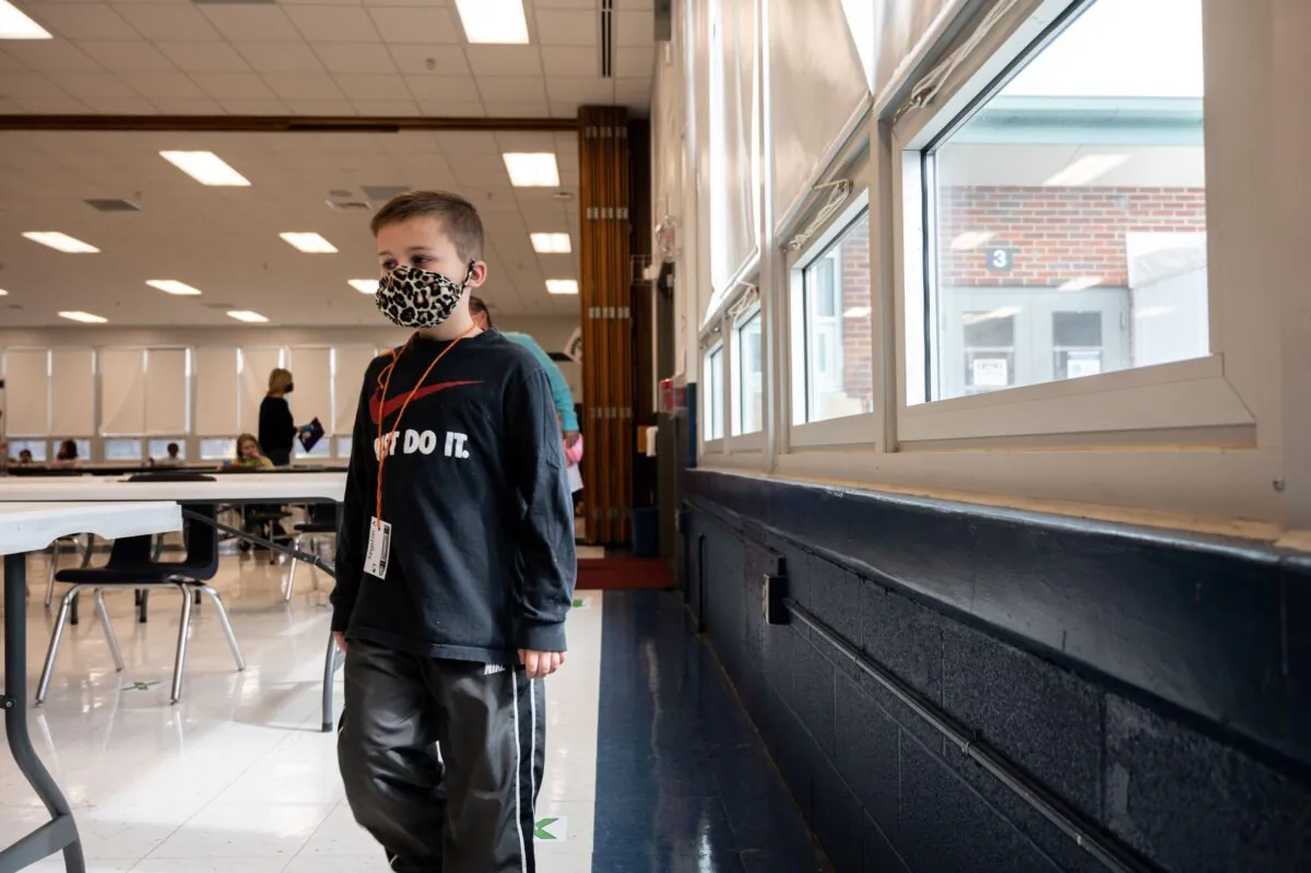 A masked student walks in line through the cafeteria at Medora Elementary School in Louisville, Ky., on March 17, 2021. (Jon Cherry/Getty Images)