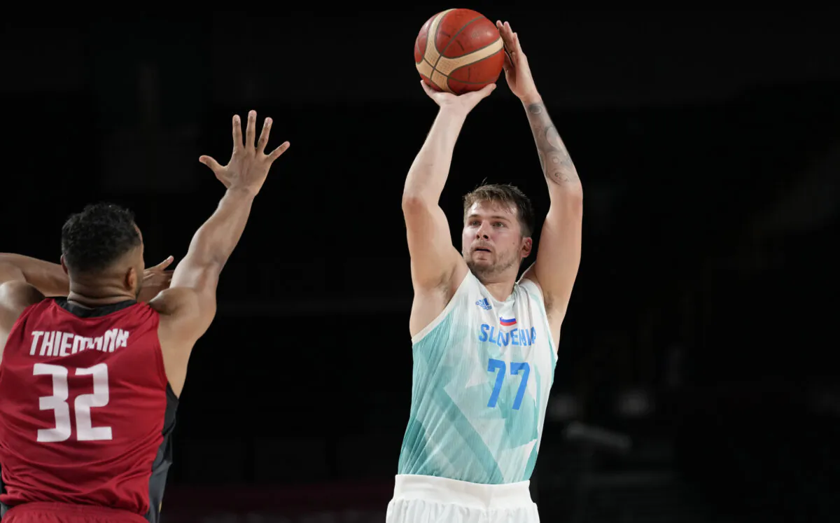Slovenia's Luka Doncic (77), right, shoots over Germany's Johannes Thiemann (32) during men's basketball quarterfinal game at the 2020 Summer Olympics, in Saitama, Japan, on Aug. 3, 2021. (Eric Gay/AP Photo)