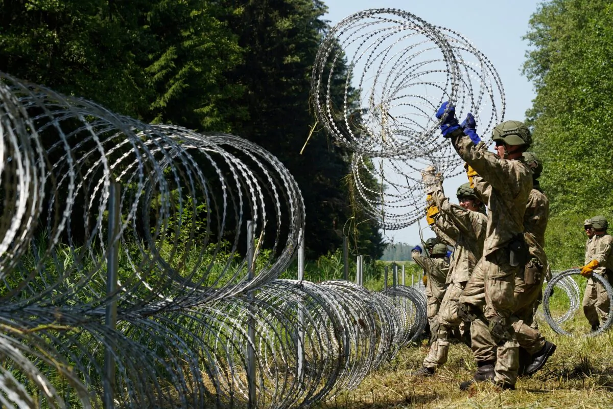 Lithuanian army soldiers install razor wire on the border with Belarus in Druskininkai, Lithuania, on July 9, 2021. (Janis Laizans/Reuters)
