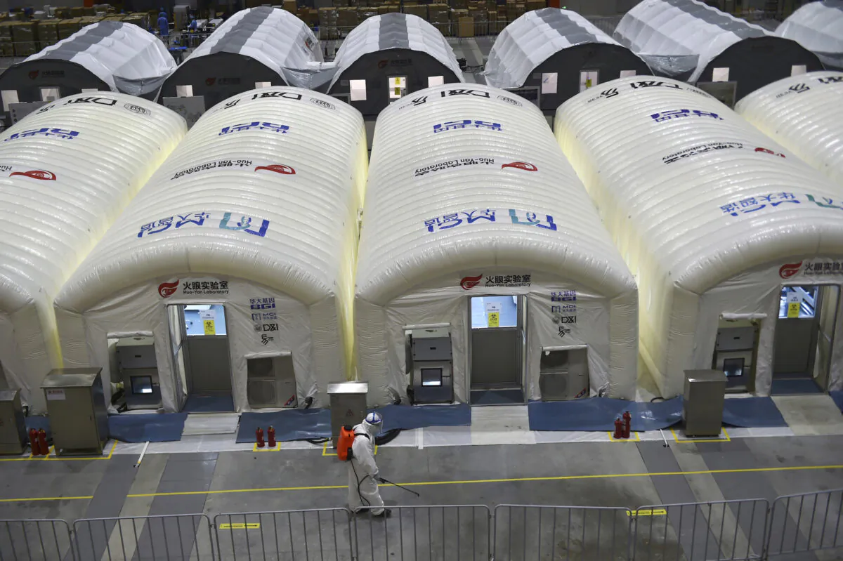 A worker disinfects the floor outside the inflated cabins at the pop-up Huo-Yan Laboratory set up to test samples for COVID-19 virus in Nanjing in east China's Jiangsu Province on July 28, 2021. (Chinatopix/Via AP) 