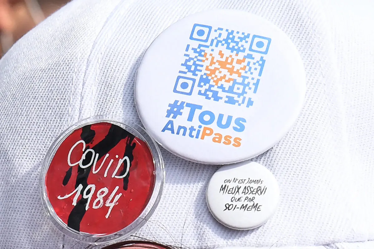 A protester wears a cap with badges reading "All against the Health pass" in a protest against the compulsory vaccination for certain workers and the mandatory use of the health pass in Paris on July 24, 2021. (Alan Jocard/AFP via Getty Images)
