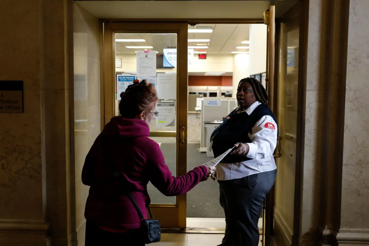 A security guard hands out an instruction sheet outside of a State of Michigan Unemployment Agency office in Cadillac Place in Detroit, Michigan on March 26, 2020. (Jeff Kowalsky/AFP via Getty Images)