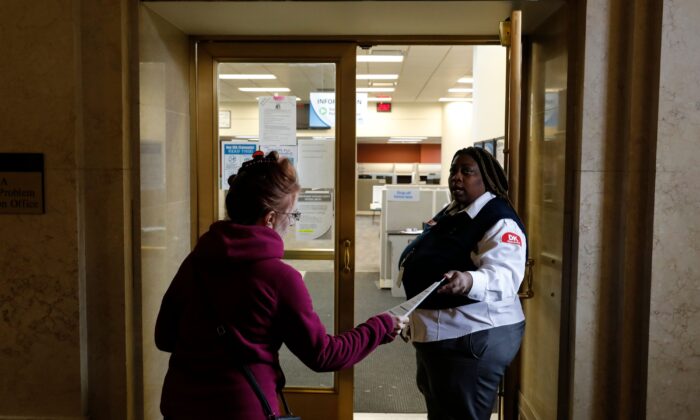 A security guard hands out an instruction sheet outside of a State of Michigan Unemployment Agency office in Cadillac Place in Detroit, Michigan on March 26, 2020. (Jeff Kowalsky/AFP via Getty Images)