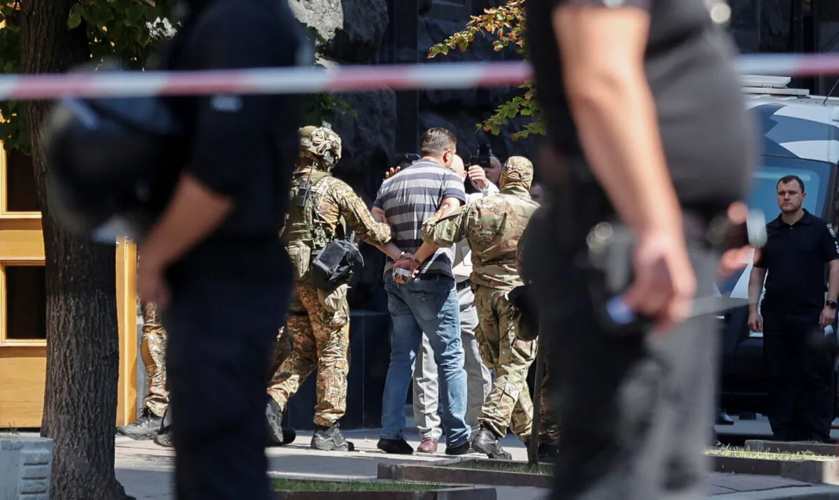 Law enforcement officers detain a man who, according to the head of the National Police, forced his way into Ukraine's main government building and threatened to detonate a grenade, in Kyiv, Ukraine, on Aug. 4, 2021. (Serhii Nuzhnenko/Reuters)