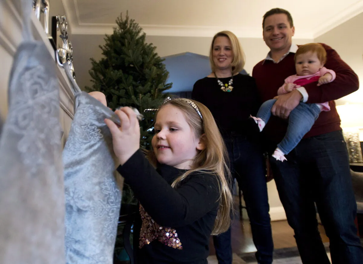 A young girl places items in a Christmas stocking as her parents and 7-month-old sister watch at their home in Toronto in a file photo. (The Canadian Press/Nathan Denette)