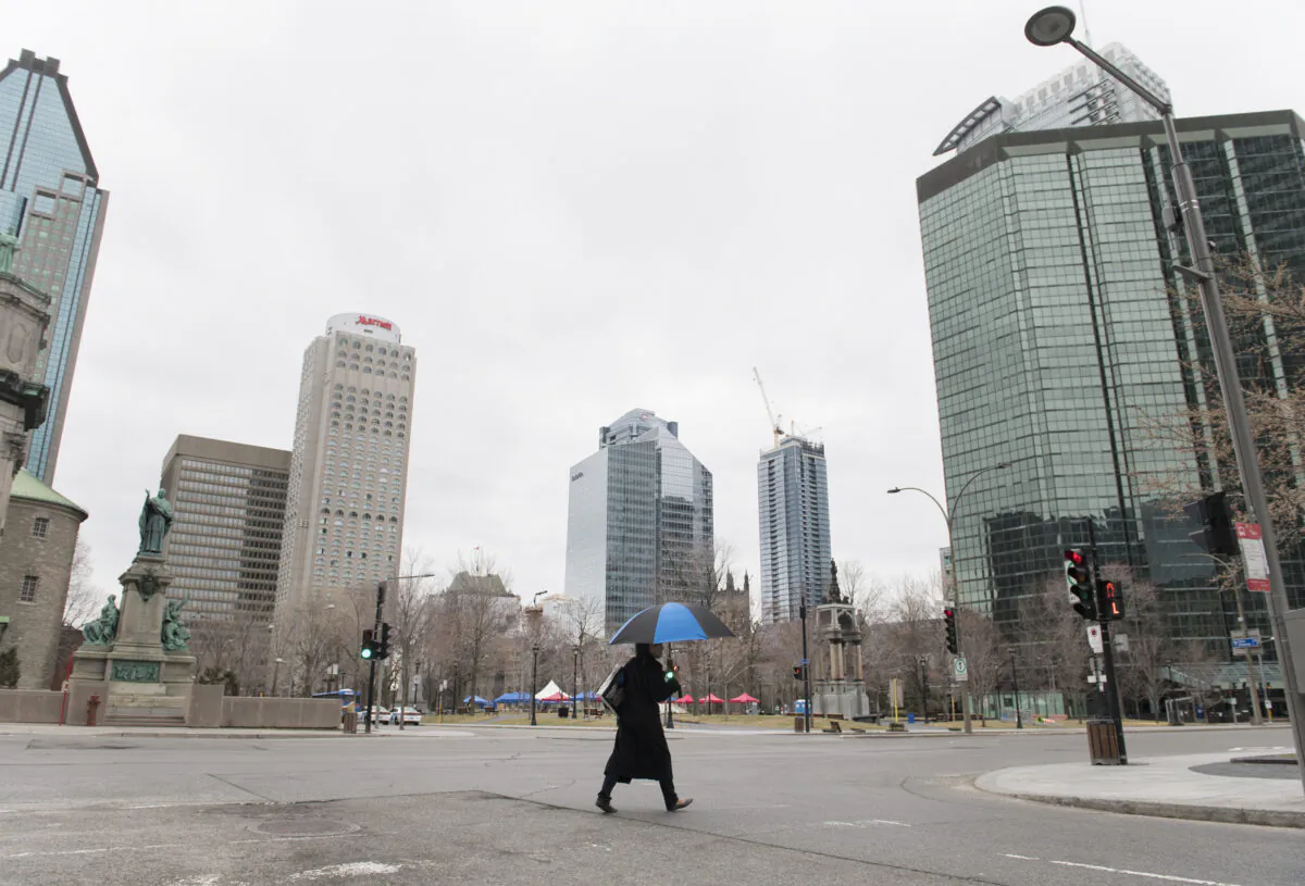 A woman crosses an empty street in downtown Montreal during a COVID pandemic lockdown on April 5, 2020. (The Canadian Press/Graham Hughes)