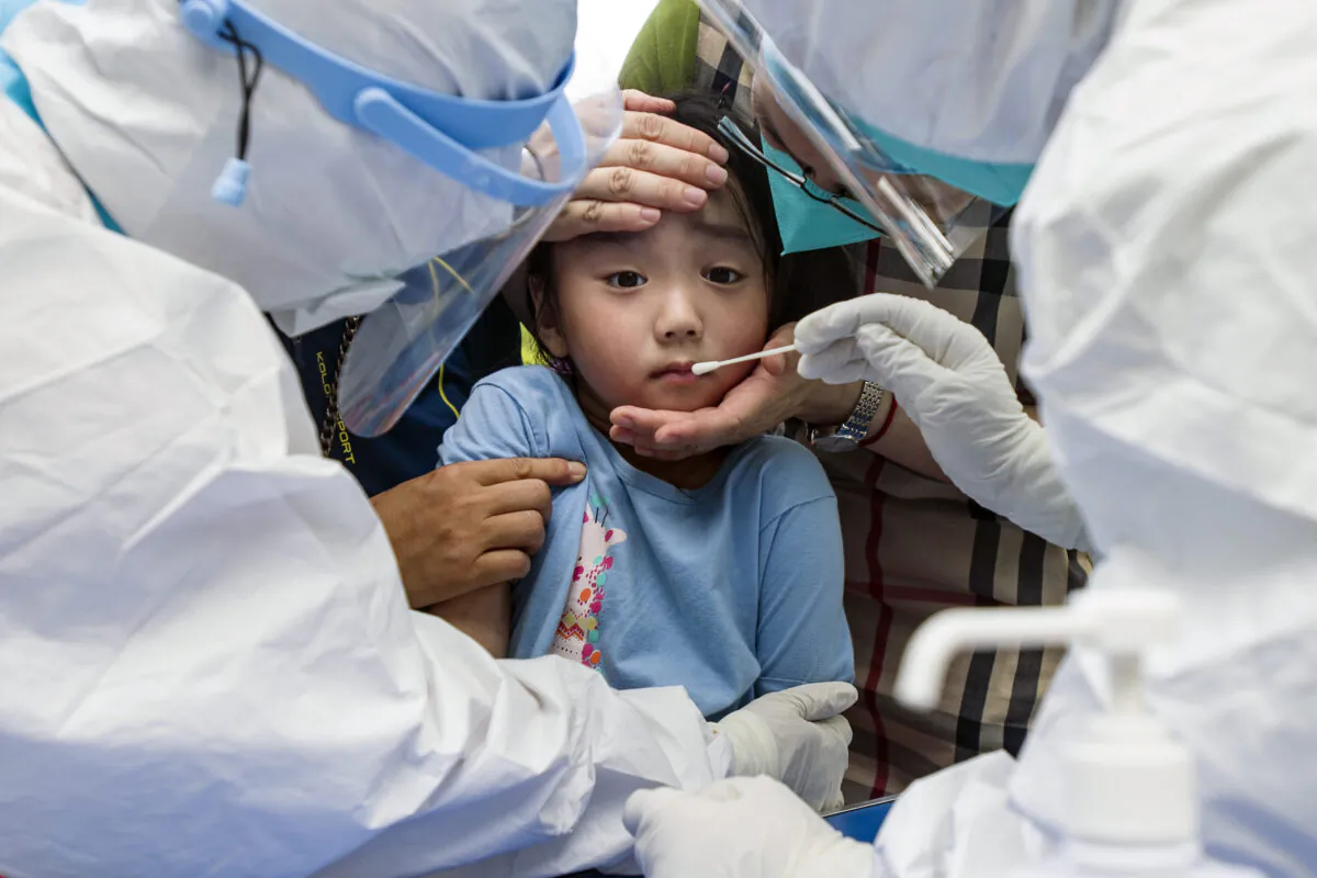 A child reacts to a throat swab during mass testing for COVID-19 in Wuhan in central China's Hubei province, on Aug. 3, 2021. (Chinatopix/via AP)