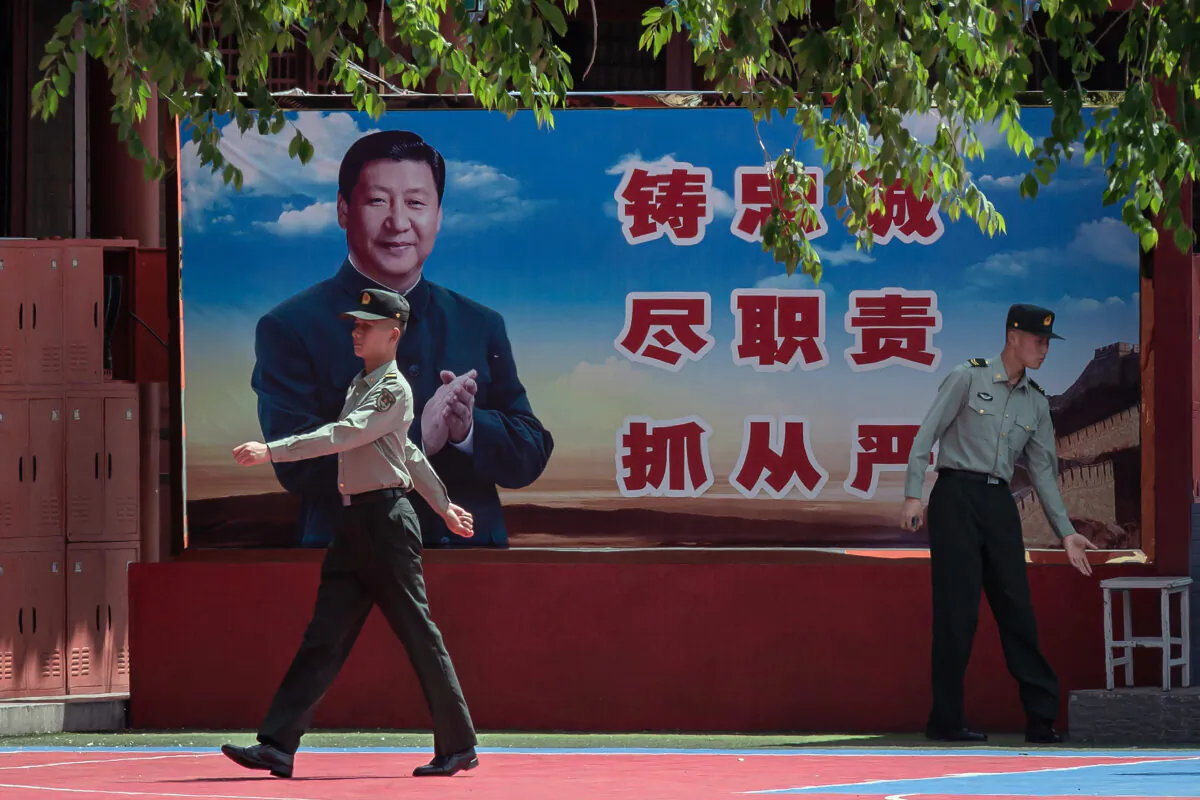 Soldiers are seen near a poster of Chinese leader Xi Jinping next to the entrance to the Forbidden City in Beijing on May 18, 2020. (Nicolas Asfouri/AFP via Getty Images) 