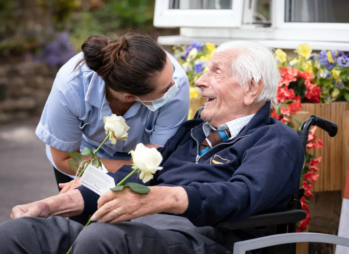 Health Care Assistant Rose Waddington and ninety-eight-year-old resident John Kykot are pictured with "thank you" white roses that were presented to them by the Mayor of West Yorkshire Tracy Brabin at Norwood House Nursing Home in Keighley, England, on July 4, 2021. (Danny Lawson/PA)