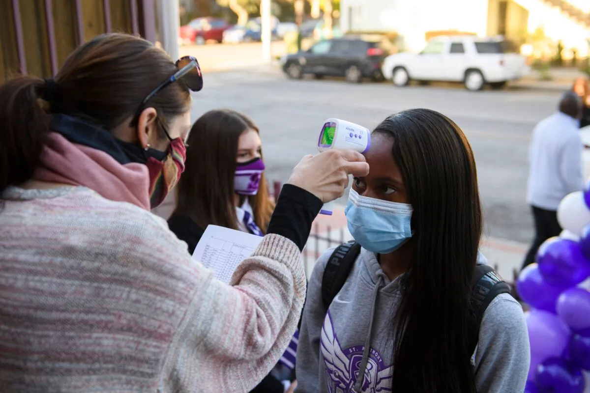 A student receives a temperature check before class as they return to in-person learning in a file photo. (Patrick T. Fallon/AFP via Getty Images)