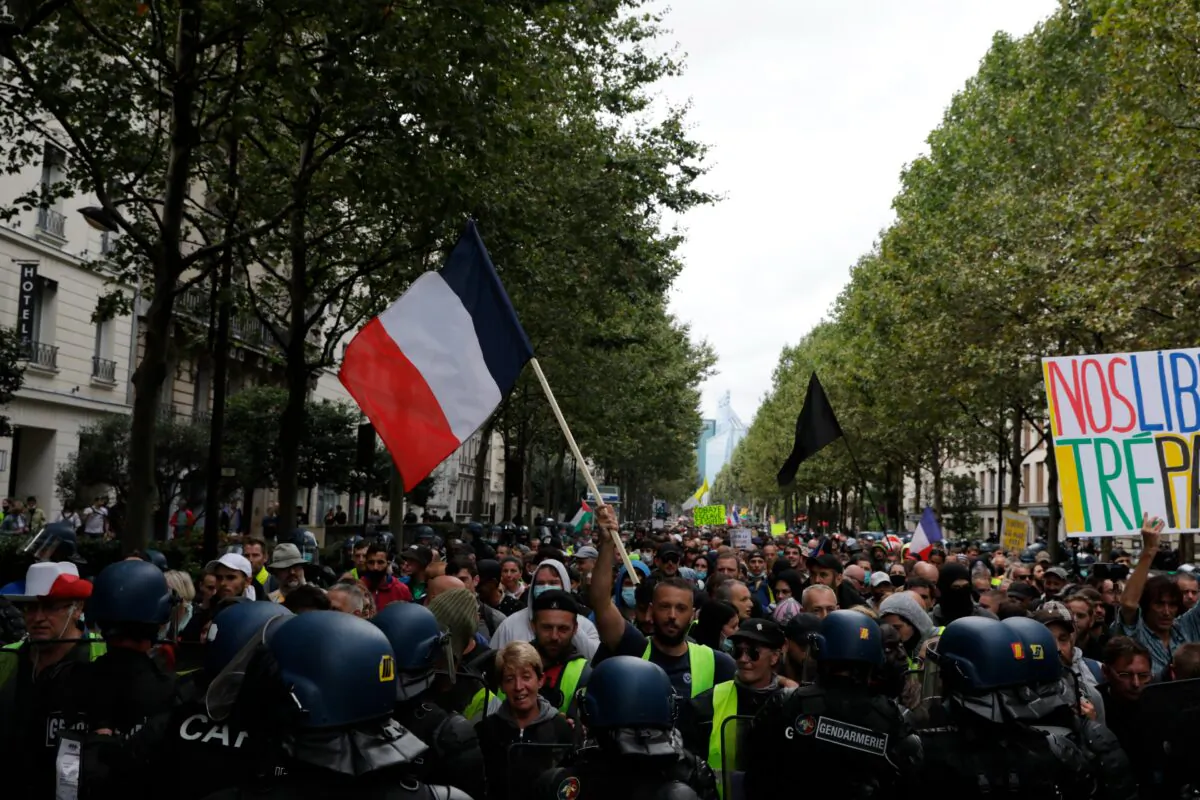 Protesters face police during a protest against the vaccine passports, in Paris, on Aug. 7, 2021. (Adrienne Surprenant /AP Photo)